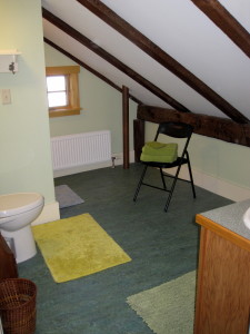 The all-new second floor bathroom is under the eaves, but what beautiful original beams! (Watch your head, tho.  :)  There is a nice shower on the left rear of the photo, ner the small casement window.  The floor is wonderful Marmoleum - real linoleum. There's a small oak cabinet and sink. 